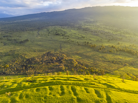 Aerial view of Puu Waawaa cinder cone featuring lush green slopes and ancient lava flows under golden hour light in Hawaii County Hawaii United States. Aerial view of Puu Waawaa cinder cone featuring lush green slopes and ancient lava flows under golden hour light in Hawaii County Hawaii United States.