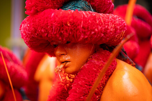 Munshiganj Bangladesh 13 April 2025 View of a performer adorned in vibrant red headwear and garlands with striking orange painted skin showcasing vivid hues and intricate textures. Munshiganj Bangladesh 13 April 2025 View of a performer adorned in vibrant red headwear and garlands with striking orange painted skin showcasing vivid hues and intricate textures.