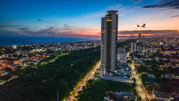 Aerial view of the Caney Tower featuring a rooftop landing pad illuminated city skyline and the Caribbean Sea at sunset in Santo Domingo Distrito Nacional Dominican Republic. Aerial view of the Caney Tower featuring a rooftop landing pad illuminated city skyline and the Caribbean Sea at sunset in Santo Domingo Distrito Nacional Dominican Republic.