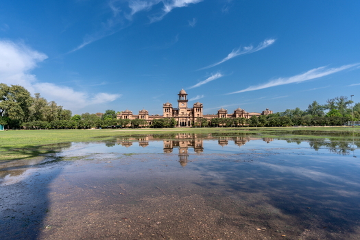 View of the historic Islamia College University Peshawar reflected in a large puddle on the foreground lawn under a clear blue sky in Peshawar Khyber Pakhtunkhwa Pakistan. View of the historic Islamia College University Peshawar reflected in a large puddle on the foreground lawn under a clear blue sky in Peshawar Khyber Pakhtunkhwa Pakistan.