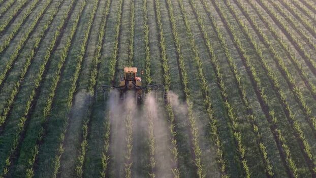Aerial view of a tractor spraying a vineyard in Targon France. Aerial view of a tractor spraying a vineyard in Targon France.