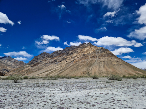 View of the rugged mountain landscape along the Penzi La road with arid slopes and rocky terrain under a bright blue sky in Zanskar Ladakh India.
