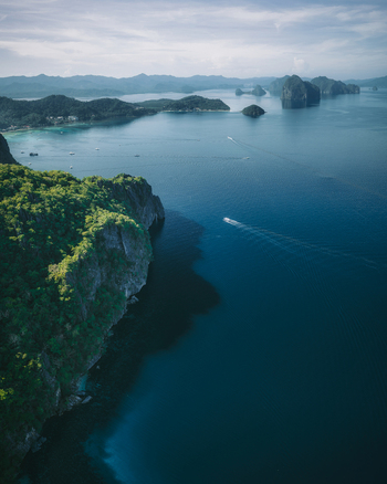 Aerial view of Papaya Beach with lush green cliffs turquoise waters and small boats in El Nido Mimaropa Philippines. Aerial view of Papaya Beach with lush green cliffs turquoise waters and small boats in El Nido Mimaropa Philippines.