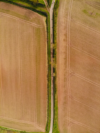 Aerial view of Castlefields area with a narrow country road flanked by hedgerows and plowed agricultural fields in Stafford England United Kingdom. Aerial view of Castlefields area with a narrow country road flanked by hedgerows and plowed agricultural fields in Stafford England United Kingdom.