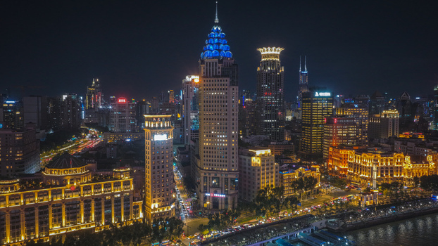 Aerial view of the illuminated skyline of The Bund at night with glowing skyscrapers city lights and busy streets along the Huangpu River in Shanghai Shanghai China. Aerial view of the illuminated skyline of The Bund at night with glowing skyscrapers city lights and busy streets along the Huangpu River in Shanghai Shanghai China.