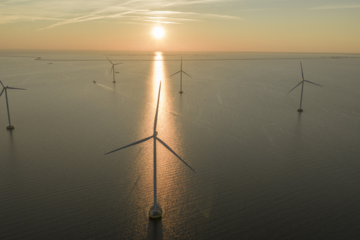 Aerial view of offshore wind turbines standing in the sea during a golden sunset with a small boat in the distance Netherlands. Aerial view of offshore wind turbines standing in the sea during a golden sunset with a small boat in the distance Netherlands.