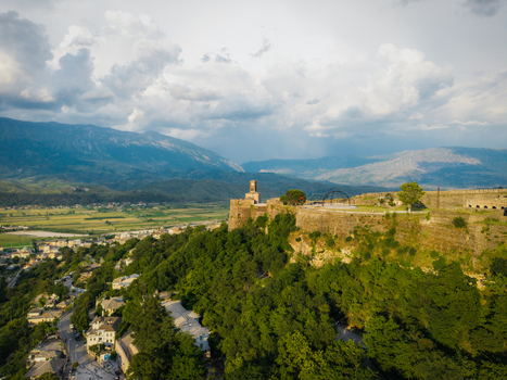 Aerial view of the historic Gjirokaster Fortress with its stone clock tower overlooking the valley and mountains in Gjirokaster Gjirokaster County Albania. Aerial view of the historic Gjirokaster Fortress with its stone clock tower overlooking the valley and mountains in Gjirokaster Gjirokaster County Albania.