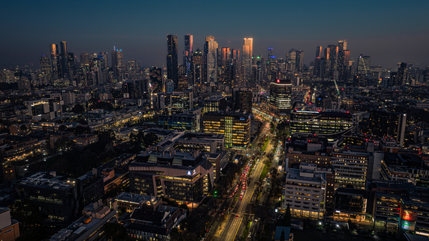 Aerial view of the Melbourne skyline at dusk with illuminated skyscrapers busy city roads and urban architecture in Parkville Victoria Australia. Aerial view of the Melbourne skyline at dusk with illuminated skyscrapers busy city roads and urban architecture in Parkville Victoria Australia.