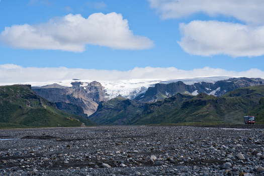 View of Thorsmork valley featuring a rocky riverbed green mountains and a glacier under a blue sky in Hvolsvollur Rangarthing eystra Iceland. View of Thorsmork valley featuring a rocky riverbed green mountains and a glacier under a blue sky in Hvolsvollur Rangarthing eystra Iceland.