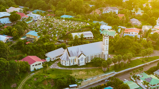 Aerial view of St. Francis of Assisi Church surrounded by lush tropical greenery a cemetery and residential houses in Mahe Baie Lazare Seychelles.