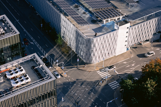 Aerial view of a modern parking structure with solar panels on the roof located at a street intersection with cars and pedestrian crossings in Vilnius Vilnius County Lithuania.