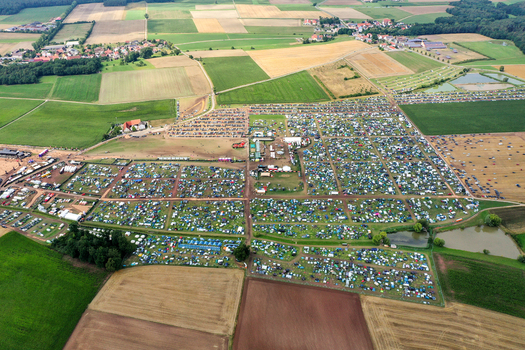 Aerial view of the Open Beatz Festival campsite with thousands of tents and parked cars surrounded by agricultural fields in Herzogenaurach Bayern Germany. Aerial view of the Open Beatz Festival campsite with thousands of tents and parked cars surrounded by agricultural fields in Herzogenaurach Bayern Germany.