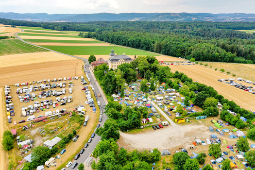 Aerial view of Schloss Jagersburg with a large campsite full of tents and parked cars surrounded by green fields and forests Eggolsheim Bayern Germany. Aerial view of Schloss Jagersburg with a large campsite full of tents and parked cars surrounded by green fields and forests Eggolsheim Bayern Germany.