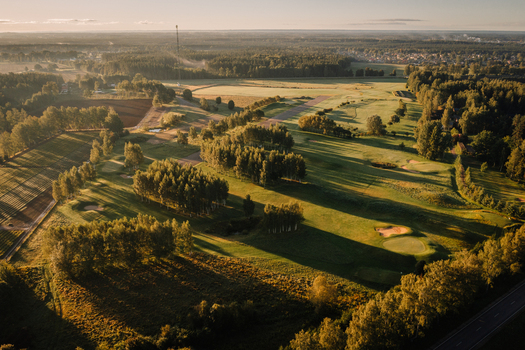 Aerial view of a golf course featuring green fairways sand bunkers and long tree shadows during golden hour in Valmiera Valmiera Latvija.
