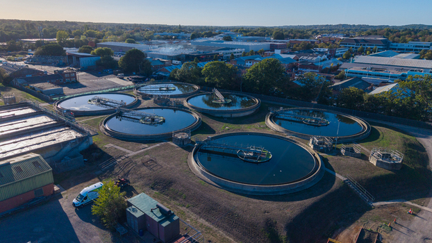 Aerial view of the Water Treatment Centre featuring large circular sedimentation tanks surrounded by industrial buildings and lush trees in Camberley England United Kingdom. Aerial view of the Water Treatment Centre featuring large circular sedimentation tanks surrounded by industrial buildings and lush trees in Camberley England United Kingdom.