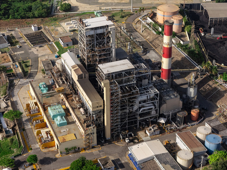 Aerial view of an industrial power plant with a tall red and white chimney storage tanks and complex machinery infrastructure in Bajos de Haina San Cristobal Provinc Dominican Republic.
