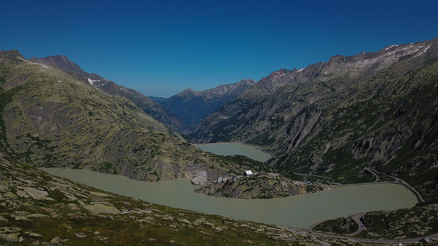 Aerial view of Grimsel Pass with turquoise alpine lakes and winding roads nestled between rugged mountain peaks in Obergoms Valais Switzerland. Aerial view of Grimsel Pass with turquoise alpine lakes and winding roads nestled between rugged mountain peaks in Obergoms Valais Switzerland.
