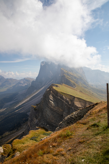 Aerial view of the Dolomites with rugged mountain peaks grassy slopes and clouds clinging to the summits in Rocca Pietore Veneto Italy.