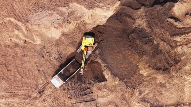 Aerial view of excavator loading truck at construction site India.