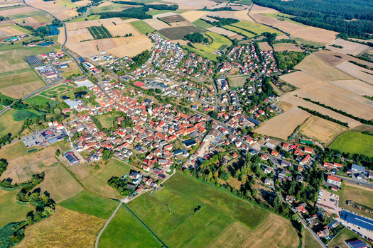 Aerial view of the town of Muhlhausen featuring red tiled roofs and residential houses surrounded by vast agricultural fields and green landscapes in Muhlhausen Bavaria Germany. Aerial view of the town of Muhlhausen featuring red tiled roofs and residential houses surrounded by vast agricultural fields and green landscapes in Muhlhausen Bavaria Germany.