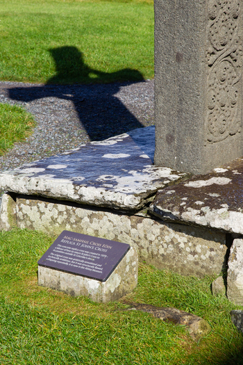 View of the stone base and plaque of St John s Cross replica with its shadow cast on the grass at the historic Iona Abbey and Nunnery in Isle of Iona Scotland United Kingdom. View of the stone base and plaque of St John s Cross replica with its shadow cast on the grass at the historic Iona Abbey and Nunnery in Isle of Iona Scotland United Kingdom.