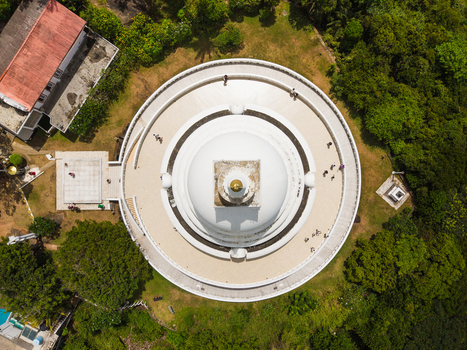 Aerial view of the Japanese Peace Pagoda Rumassala with people walking on the circular terrace surrounded by lush green forest Unawatuna Southern Province Sri Lanka. Aerial view of the Japanese Peace Pagoda Rumassala with people walking on the circular terrace surrounded by lush green forest Unawatuna Southern Province Sri Lanka.