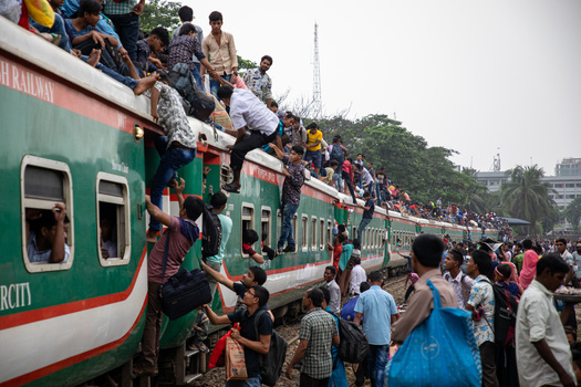 Dhaka Bangladesh 15 June 2018 View of people climbing onto the roof and hanging from the doors of a crowded train at Airport Railway Station during a busy commute. Dhaka Bangladesh 15 June 2018 View of people climbing onto the roof and hanging from the doors of a crowded train at Airport Railway Station during a busy commute.