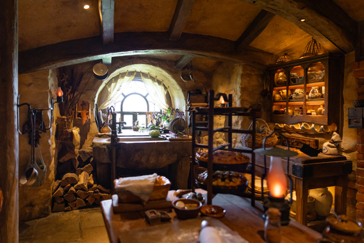 View of a cozy hobbit kitchen with stone sink wooden shelves and warm lantern light creating a homely ambiance Hobbiton Movie Set Waikato Region New Zealand. View of a cozy hobbit kitchen with stone sink wooden shelves and warm lantern light creating a homely ambiance Hobbiton Movie Set Waikato Region New Zealand.