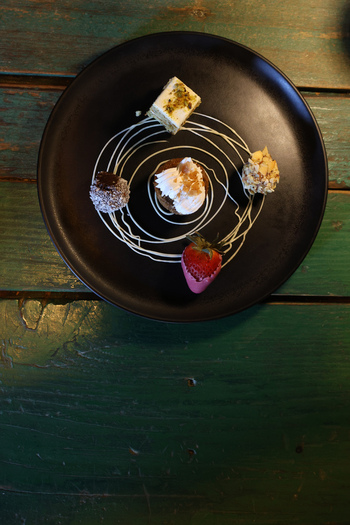 View of a gourmet dessert assortment with cake truffle nut covered treat and strawberry on a black plate at Ruba s Bakery Bistro in San Jose del Cabo Baja California Sur Mexico.