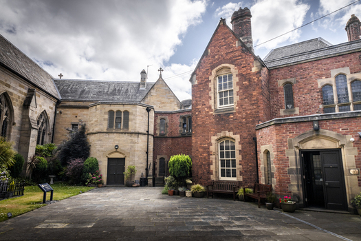 View of the historic courtyard with red brick and stone architecture wooden benches and potted plants in Newcastle upon Tyne England United Kingdom. View of the historic courtyard with red brick and stone architecture wooden benches and potted plants in Newcastle upon Tyne England United Kingdom.