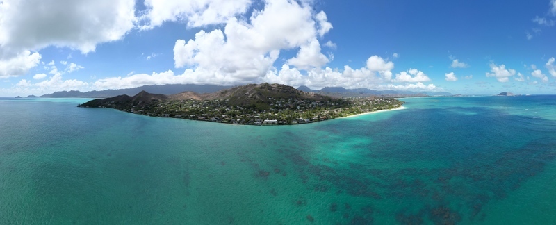 Aerial view of the serene Lanikai Beach where the turquoise ocean meets the soft white sand under a sky dotted with fluffy clouds Kailua Hawaii United States. Aerial view of the serene Lanikai Beach where the turquoise ocean meets the soft white sand under a sky dotted with fluffy clouds Kailua Hawaii United States.