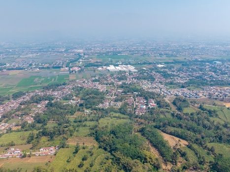 Aerial view of the city of Malang surrounded by lush agricultural fields residential neighborhoods and tropical greenery in Malang East Java Indonesia.