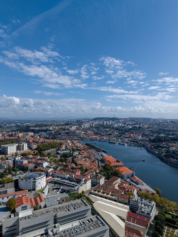 Aerial view of Porto featuring the Douro River winding through historic terracotta roofed buildings and urban infrastructure under a clear blue sky in Porto Porto District Portugal.