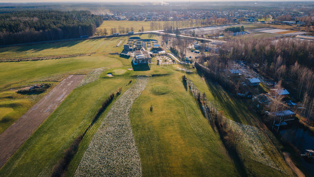 Valmiera Latvija 18 November 2025 Aerial view of the golf club building and course on a frosty morning with green fairways surrounding forest and clear blue sky.
