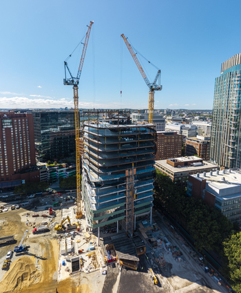 Aerial view of the Kendall Square construction site featuring a high rise building under development with two tall yellow cranes in Cambridge Massachusetts United States. Aerial view of the Kendall Square construction site featuring a high rise building under development with two tall yellow cranes in Cambridge Massachusetts United States.