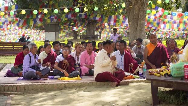 View of people praying under prayer flags in Lumbini Nepal.