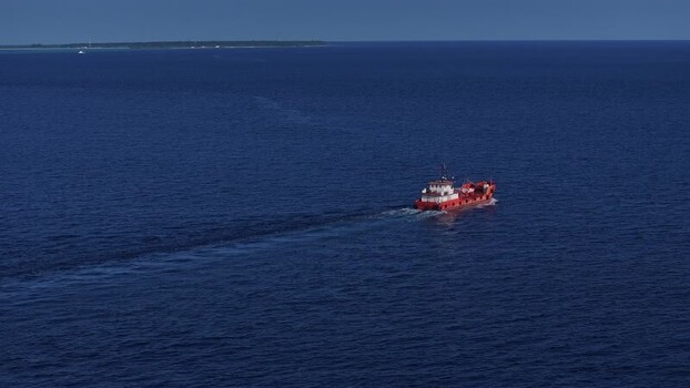 Aerial view of a red cargo ship in the ocean Maldives. Aerial view of a red cargo ship in the ocean Maldives.