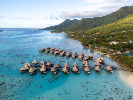Aerial view of Sofitel Kia Ora Moorea Beach Resort with overwater bungalows in the turquoise lagoon lush green mountains and clear sky in Moorea Maiao Windward Islands French Polynesia. Aerial view of Sofitel Kia Ora Moorea Beach Resort with overwater bungalows in the turquoise lagoon lush green mountains and clear sky in Moorea Maiao Windward Islands French Polynesia.