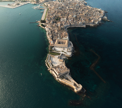 Aerial view of the Island of Ortigia and Maniace Castle surrounded by the turquoise Mediterranean Sea in Syracuse Sicily Italy. Aerial view of the Island of Ortigia and Maniace Castle surrounded by the turquoise Mediterranean Sea in Syracuse Sicily Italy.