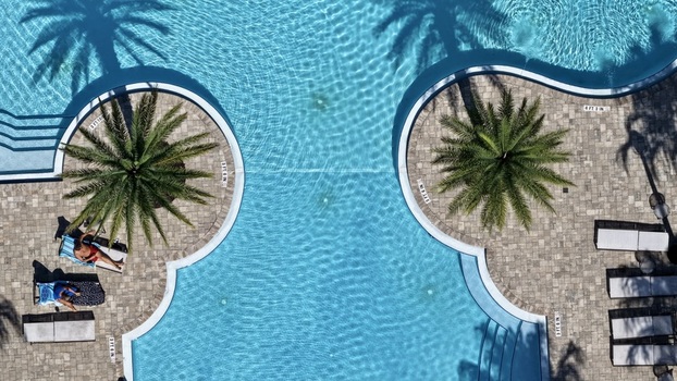 Aerial view of a swimming pool at Windward Ranch Boulevard with palm trees lounge chairs and people relaxing by the water in St. Johns County Florida United States. Aerial view of a swimming pool at Windward Ranch Boulevard with palm trees lounge chairs and people relaxing by the water in St. Johns County Florida United States.