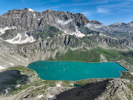 Aerial view of Serru Lake with turquoise water surrounded by rugged mountain peaks and green alpine slopes in Ceresole Reale Piedmont Italy. Aerial view of Serru Lake with turquoise water surrounded by rugged mountain peaks and green alpine slopes in Ceresole Reale Piedmont Italy.