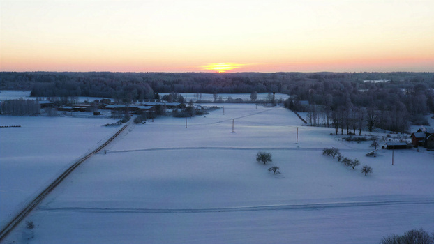 Aerial view of a snow covered landscape at sunrise with frost covered trees and open fields in Latvia. Aerial view of a snow covered landscape at sunrise with frost covered trees and open fields in Latvia.