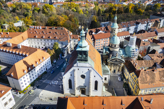 Aerial view of the Mausoleum of Emperor Ferdinand II a prominent landmark with its distinctive dome and adjacent church standing amidst a tapestry of terracotta rooftops Graz Styria Austria.