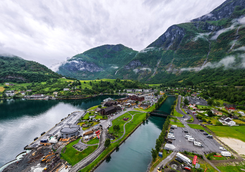 Aerial view of Flam village nestled in the Aurlandsfjord valley surrounded by lush green mountains waterfalls and calm fjord waters in Flam Vestland Norway. Aerial view of Flam village nestled in the Aurlandsfjord valley surrounded by lush green mountains waterfalls and calm fjord waters in Flam Vestland Norway.