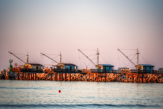 View of traditional fishing platforms known as trabucchi on a stone pier at sunset in Fano Marche Italy. View of traditional fishing platforms known as trabucchi on a stone pier at sunset in Fano Marche Italy.