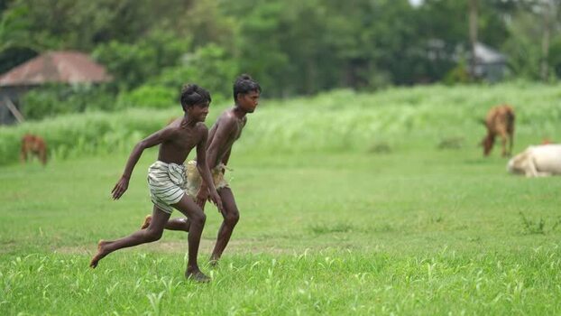 View of two young boys running through a green field Bangladesh. View of two young boys running through a green field Bangladesh.