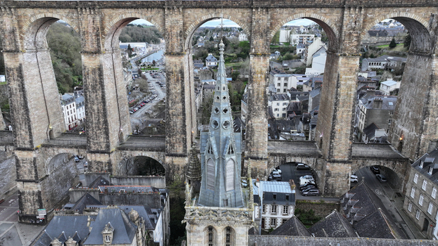 Aerial view of the Eglise Saint Melaine spire framed by the massive stone arches of the historic railway viaduct and town rooftops in Morlaix Bretagne France. Aerial view of the Eglise Saint Melaine spire framed by the massive stone arches of the historic railway viaduct and town rooftops in Morlaix Bretagne France.