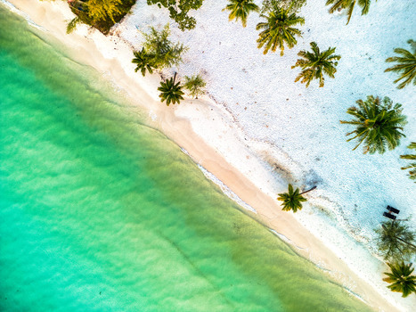 Aerial view of the turquoise water gently kissing the pristine white sands fringed by vibrant green palm trees Preah Sihanouk Sihanoukville Cambodia.