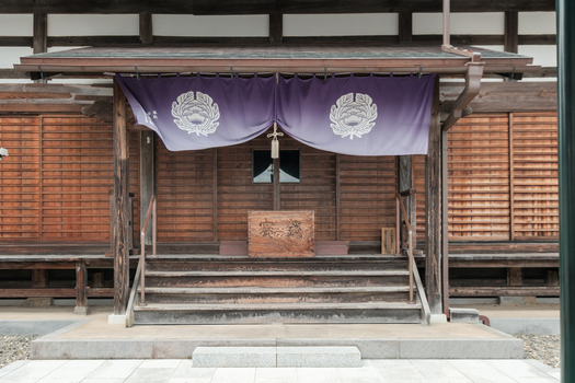 View of an ornate temple entrance featuring wooden steps a purple curtain with emblems and intricate details Narita Chiba Japan. View of an ornate temple entrance featuring wooden steps a purple curtain with emblems and intricate details Narita Chiba Japan.