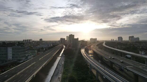 Aerial view of the highway and urban skyline of Bekasi Barat at sunset with a canal running alongside the road and modern buildings in Bekasi Barat West Java Indonesia. Aerial view of the highway and urban skyline of Bekasi Barat at sunset with a canal running alongside the road and modern buildings in Bekasi Barat West Java Indonesia.